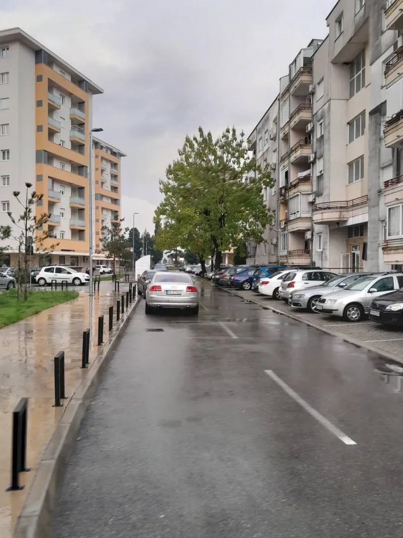 Pogled na stambene zgrade i parking ispred njih.