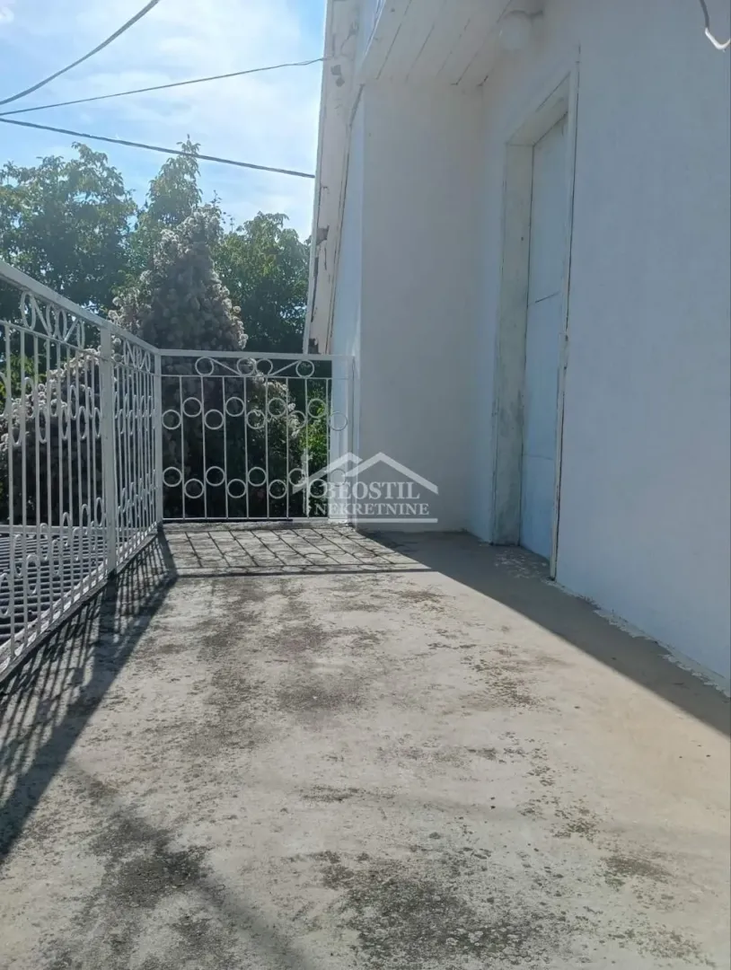Balcony with a white metal railing and a view of greenery.