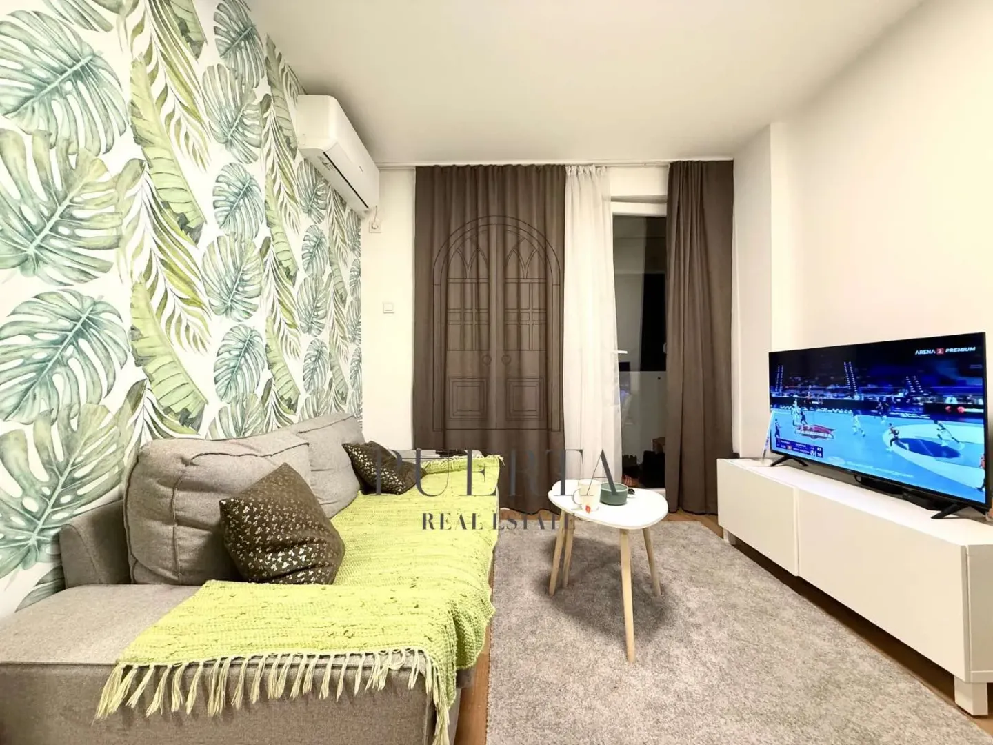 Living room with sofa, TV, and decorative wallpaper.