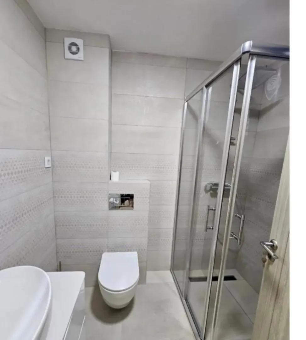 A modernly equipped bathroom with a shower cabin and light-toned sanitary ware.