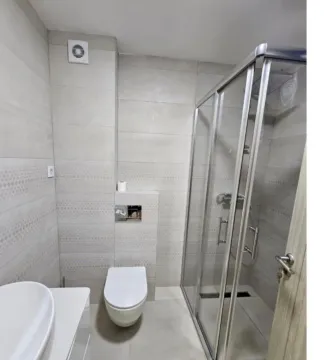 A modernly equipped bathroom with a shower cabin and light-toned sanitary ware. - image 10