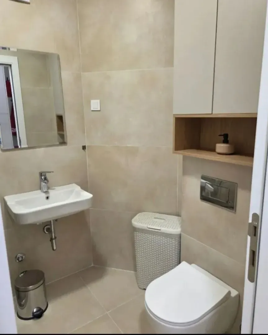 Small bathroom with a sink, toilet, and wall cabinet in beige tones.