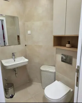 Small bathroom with a sink, toilet, and wall cabinet in beige tones. - image 10