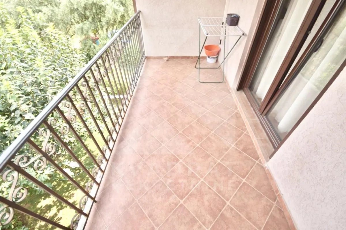 Small tiled balcony with metal railing and green views.