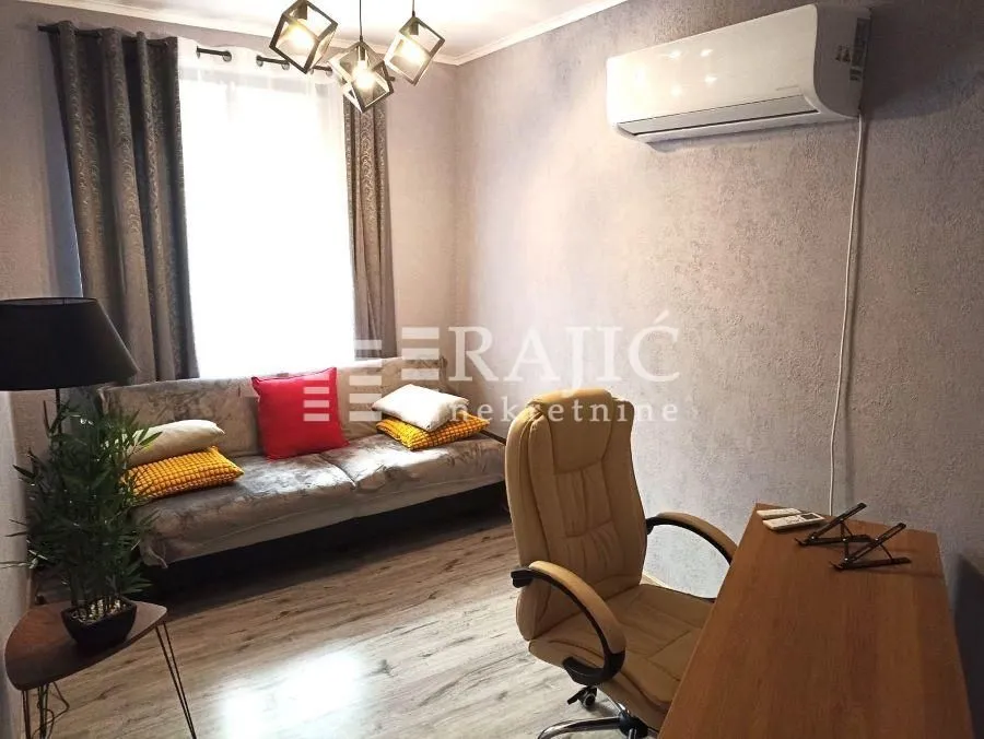 Living room with sofa, desk, and air conditioning unit.