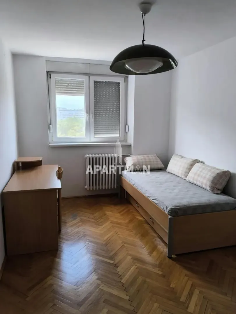 Smaller bedroom with a bed, desk, and a window.