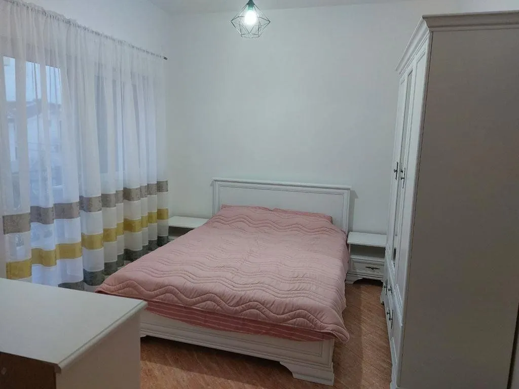 Bedroom with a double bed, white wardrobe, and a window with curtains.
