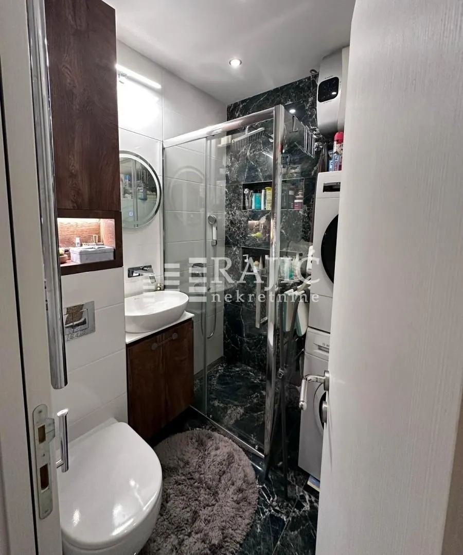 Modern bathroom with a walk-in shower, washbasin, toilet, and washing machine.
