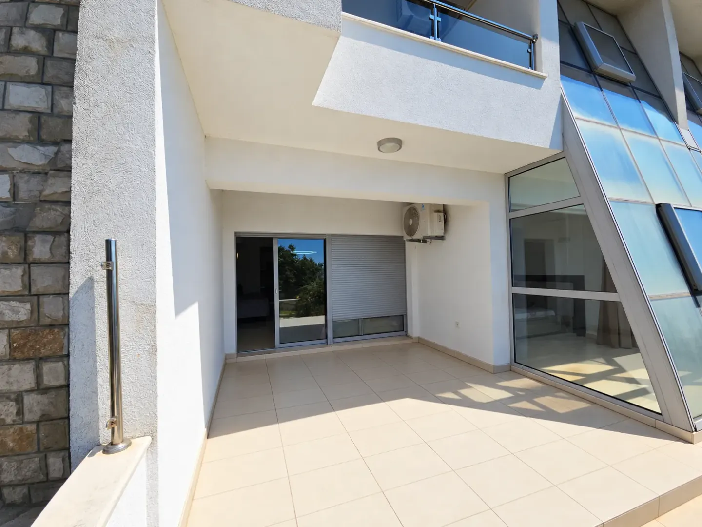 Spacious tiled terrace with a modern facade and glass elements.