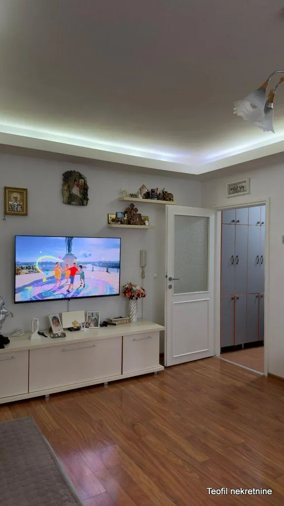 Dnevna soba sa televizorom, komodom i prolazom ka hodniku.