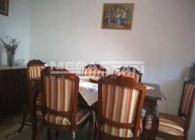 Trpezarija sa drvenim stolom i stolicama sa prugastim presvlakama.