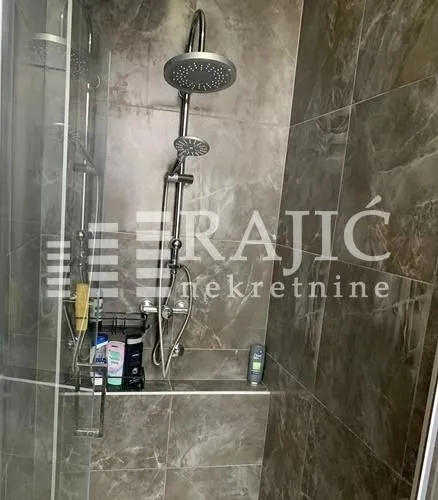Modernly equipped bathroom with a shower cabin and marble tiles.