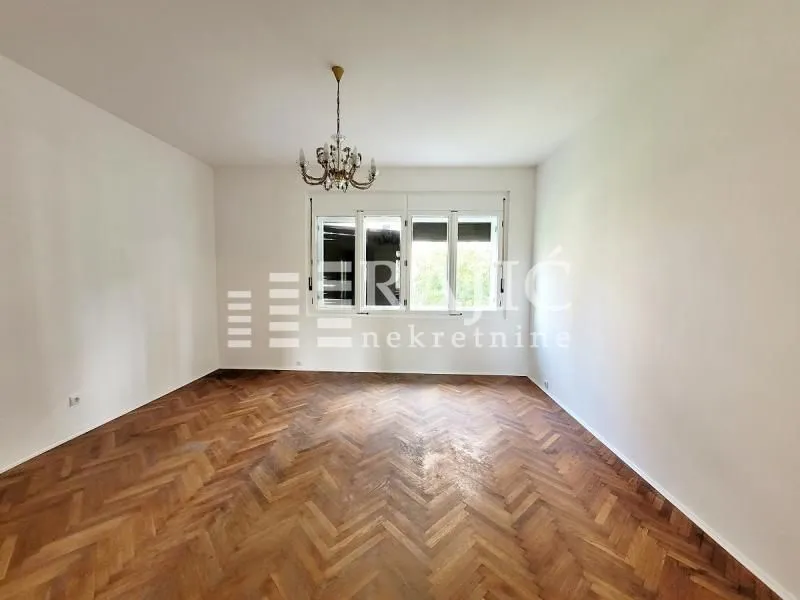 Empty room with parquet flooring and a chandelier.