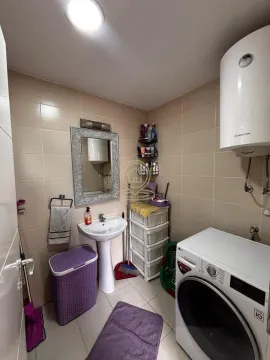 Small bathroom with a washbasin, washing machine, and water heater. - image 11