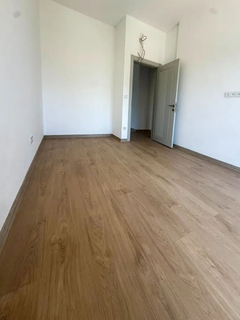 Prazna neopremljena soba sa drvenim podom i otvorenim vratima.