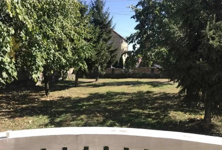 Pogled iz dvorišta na zelenu površinu i okolno zelenilo.