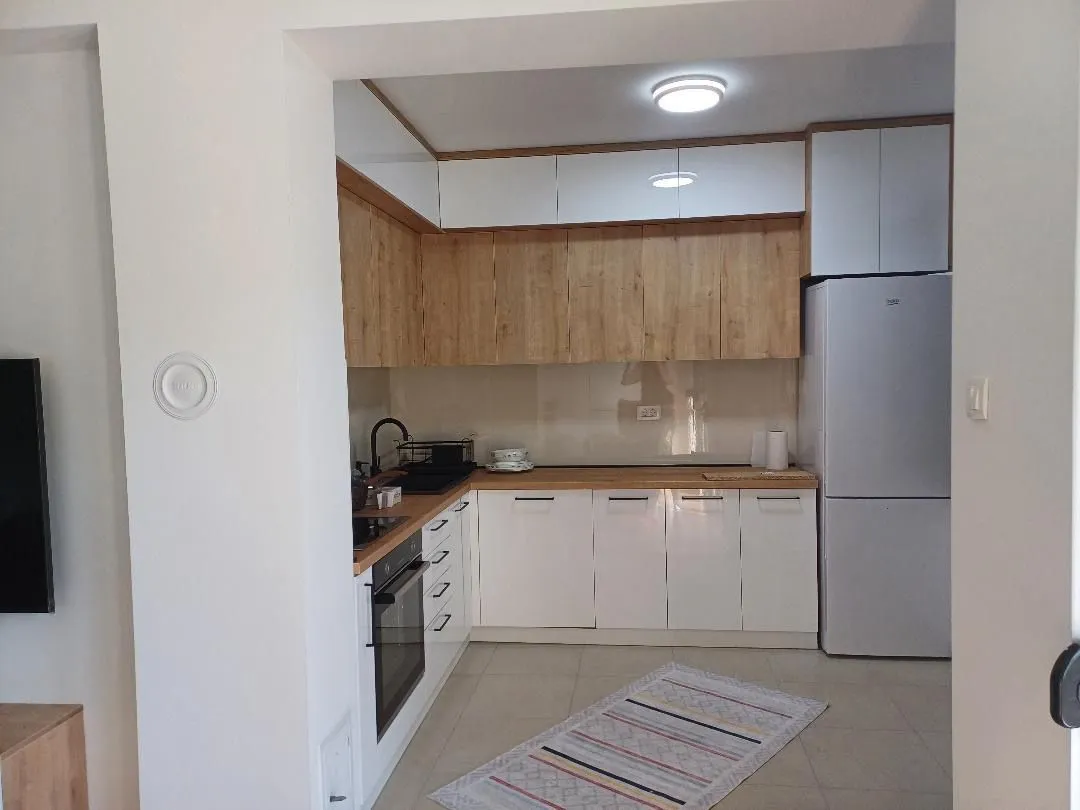 A view of a modern equipped kitchen with white cabinets and wooden details.