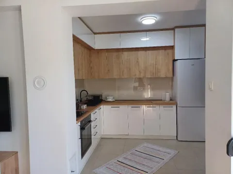 A view of a modern equipped kitchen with white cabinets and wooden details. - image 5