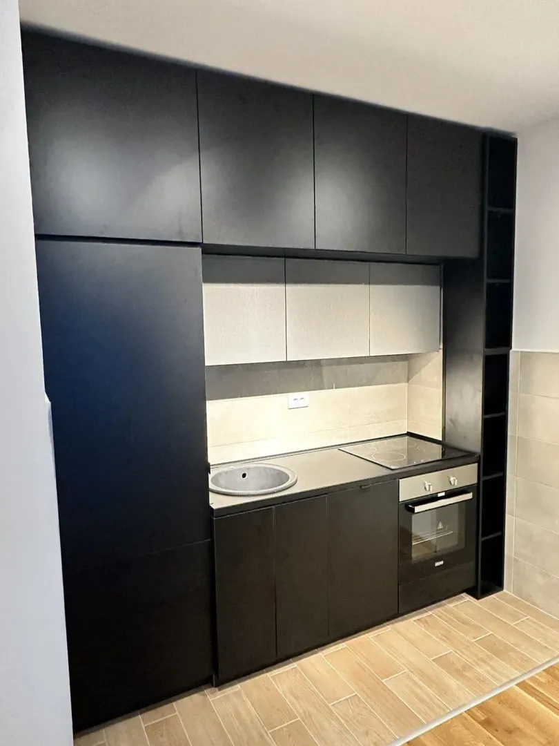 Modern black and grey kitchen with built-in appliances.