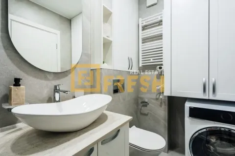 Modern bathroom with a sink, white cabinets, toilet and washing machine. - image 5