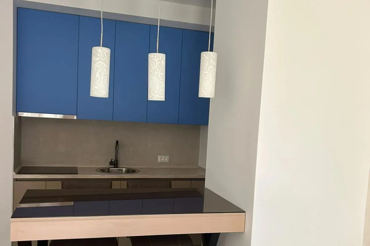 Moderna kuhinja sa plavim gornjim elementima i šankom.