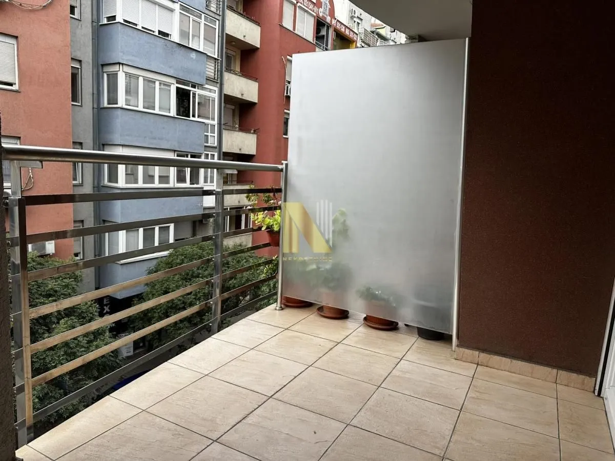 Manji popločani balkon sa metalnom ogradom i pogledom na okolne zgrade.