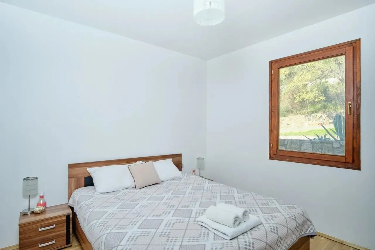 Bright bedroom with a double bed, wooden nightstands, and a window.
