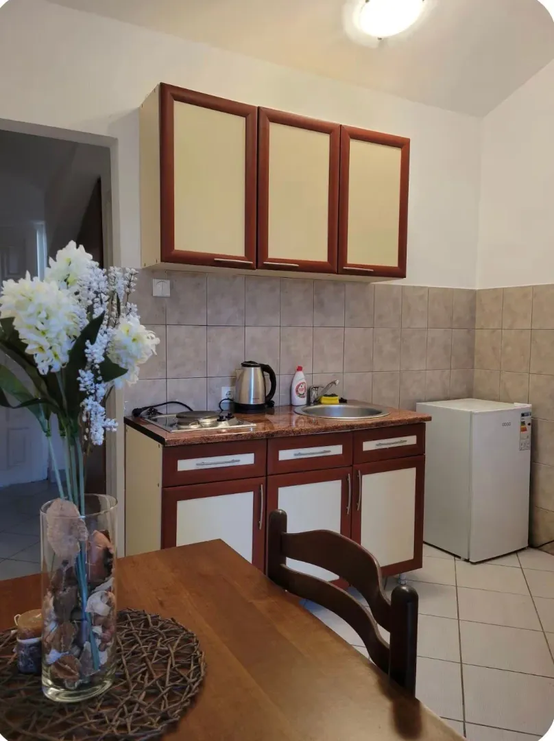 Compact kitchen with brown and white cabinets and a dining table in the foreground.