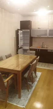 Trpezarija sa drvenim stolom i kuhinja u pozadini. - image 2