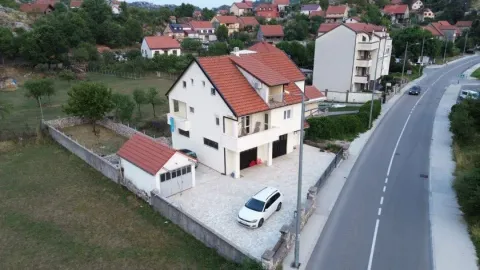 Pogled iz vazduha na kuću sa dvorištem, garažom i parkingom pored puta. - image 7