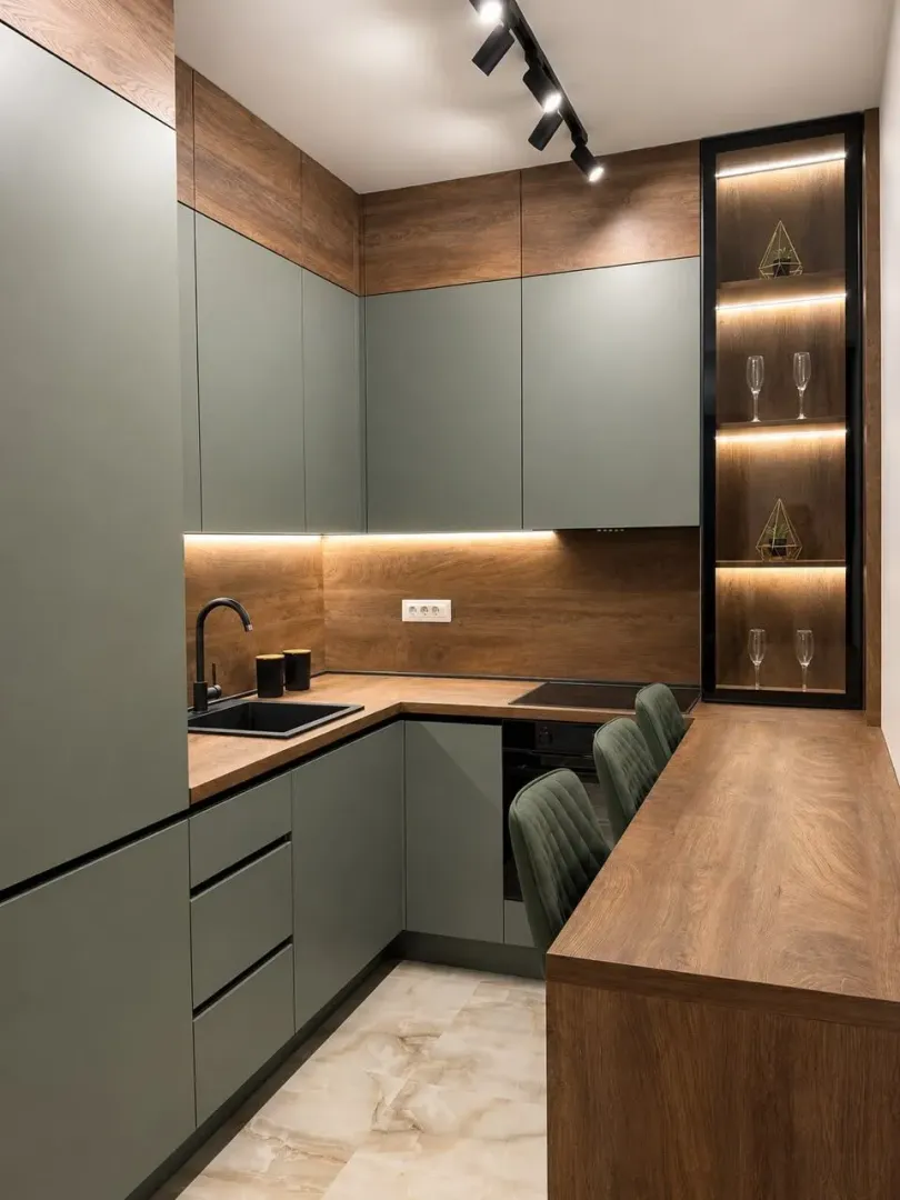 Modern kitchen with green fronts and wooden details.