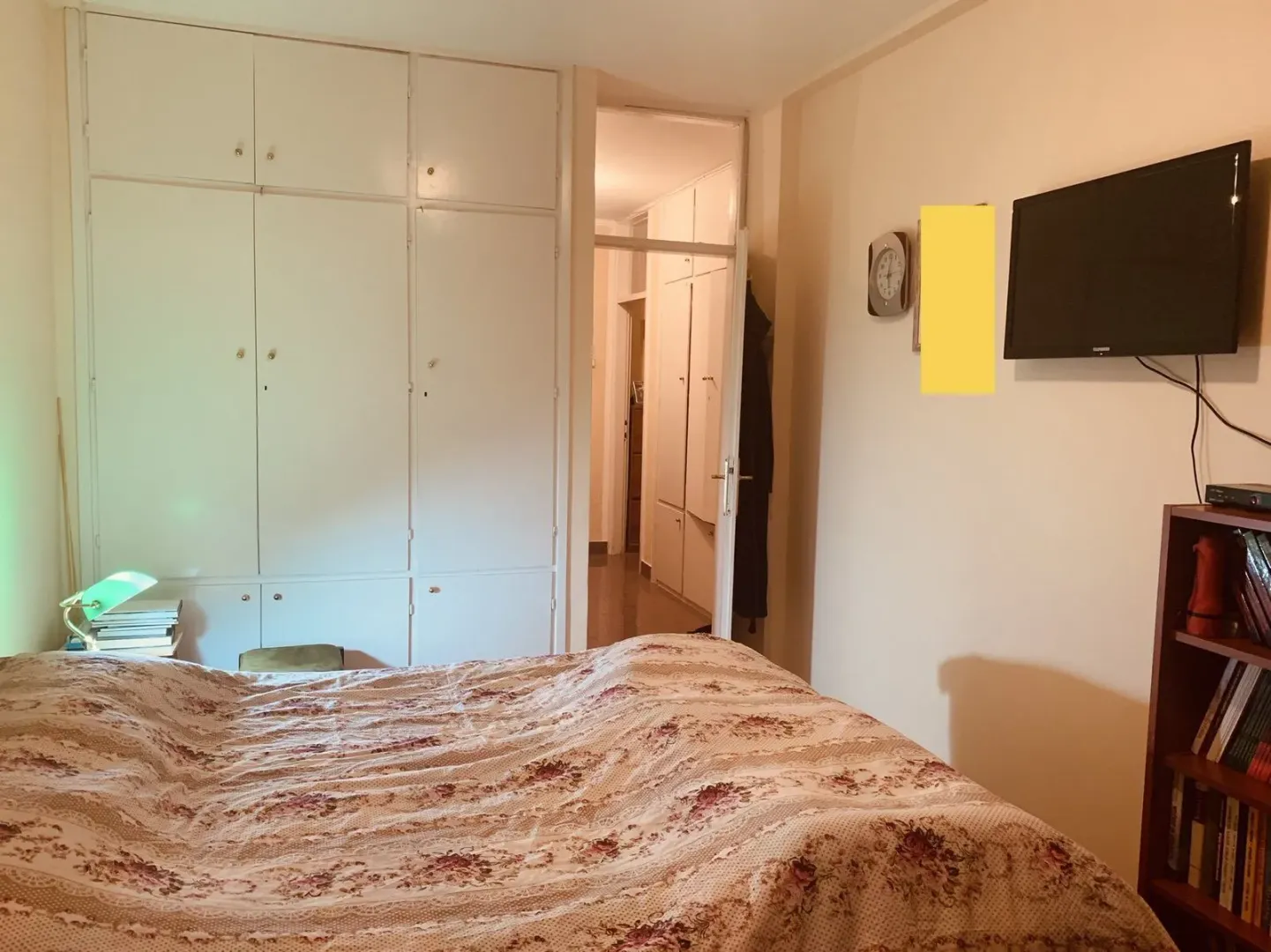 A bedroom with built-in wardrobes, a TV, and a view of the hallway.
