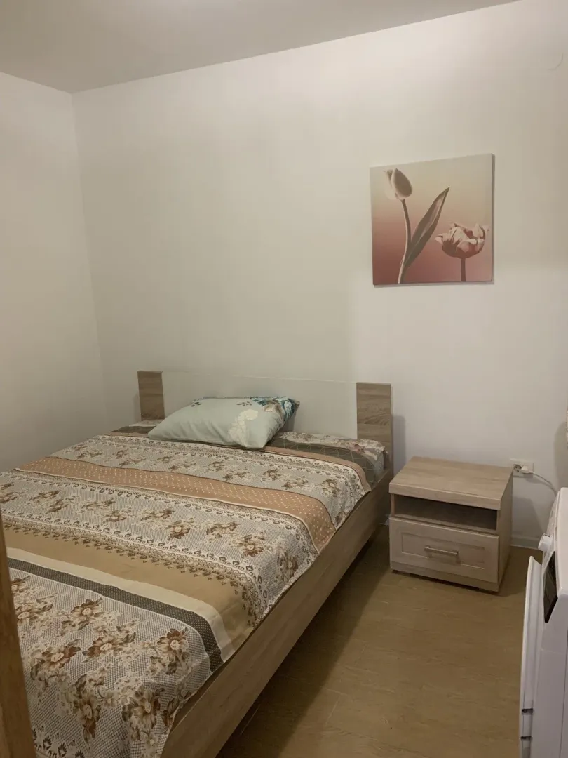 A bright bedroom featuring a double bed and a wooden nightstand.