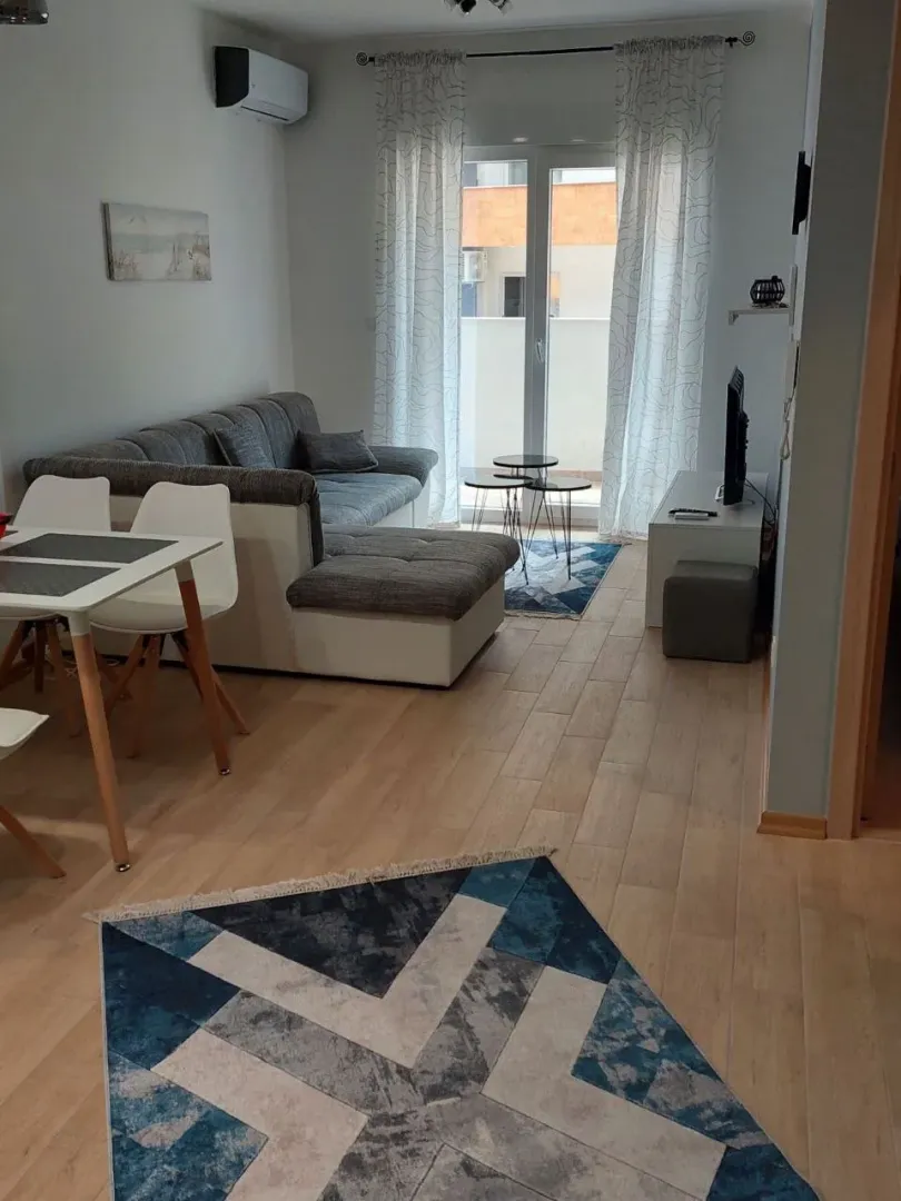 Dnevna soba sa garniturom, trpezarijskim stolom i izlazom na terasu.
