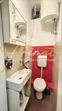 Smaller bathroom with a washbasin, toilet, and water heater. - image 5