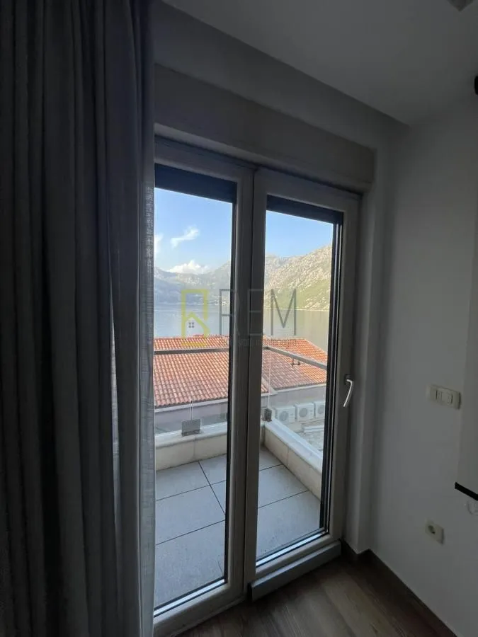 Pogled kroz balkonska vrata prema moru i planinama.