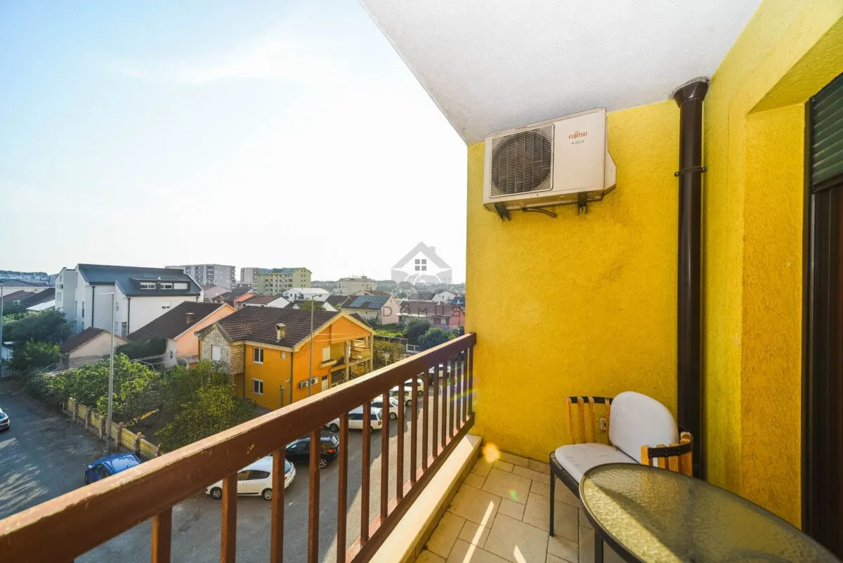 Covered balcony with seating furniture and a view of the neighborhood.