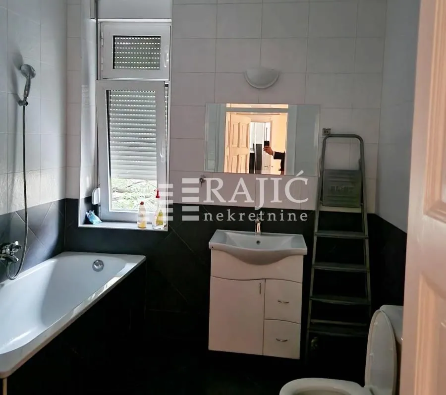 Small equipped bathroom with bathtub, washbasin, and toilet.