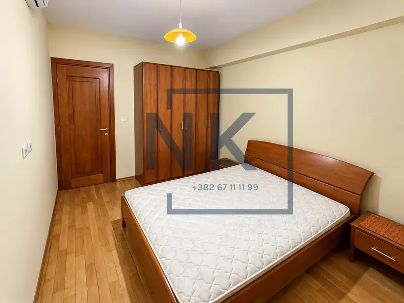 Furnished bedroom with a double bed, wardrobe, and wooden flooring.