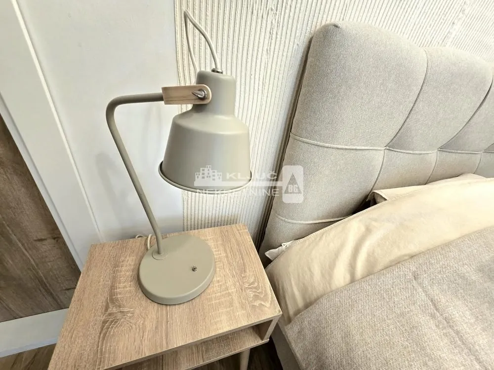 Detail of the bedroom with a bed, bedside table, and lamp.
