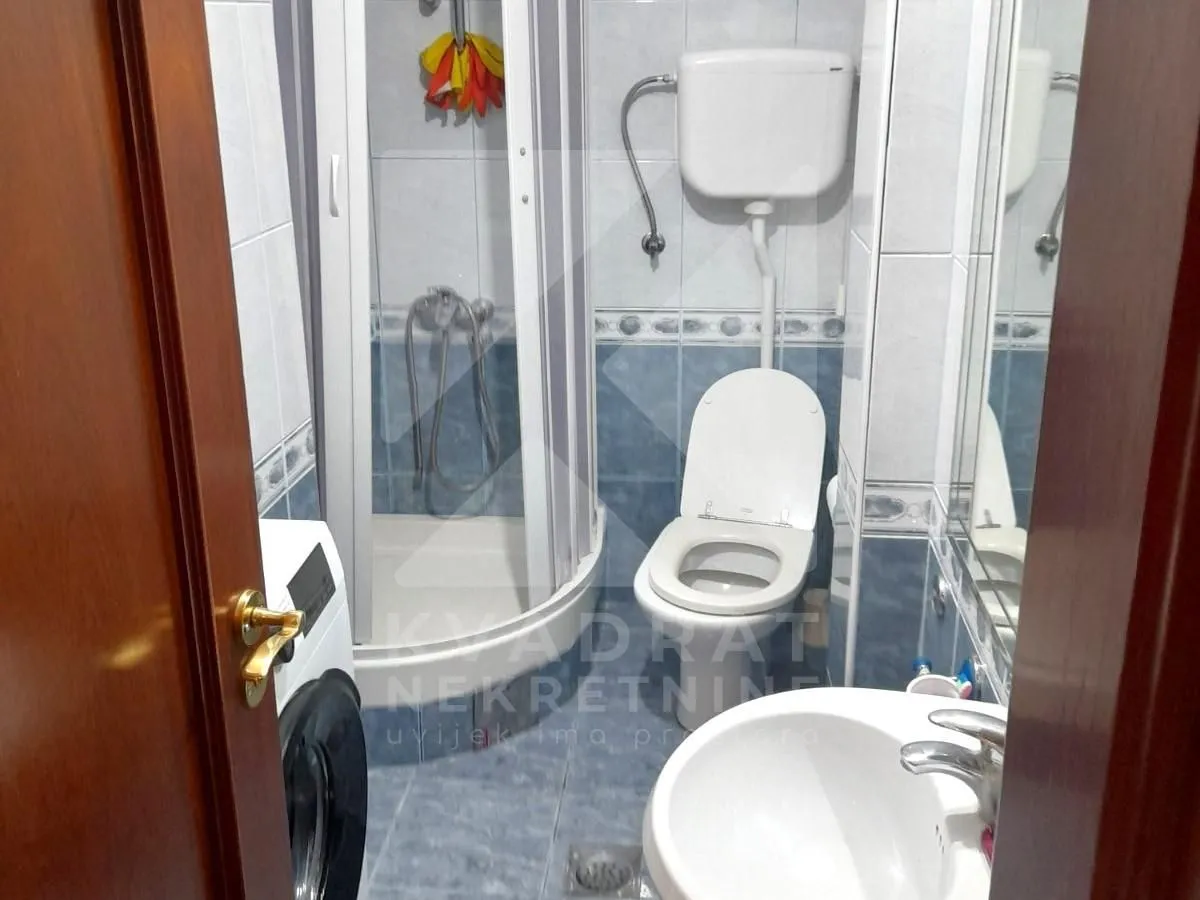Pogled na kupatilo sa tuš kabinom, WC šoljom i umivaonikom.