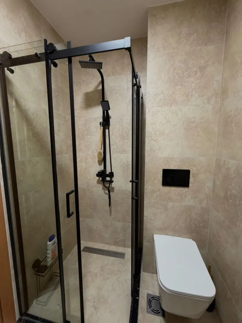 Modern bathroom equipped with a shower cabin and black fixtures.