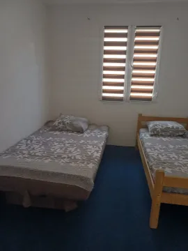 Spavaća soba sa dva kreveta i prozorom. - image 2