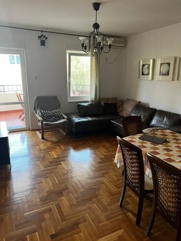 Dnevna soba sa garniturom, trpezarijskim stolom i izlazom na terasu.