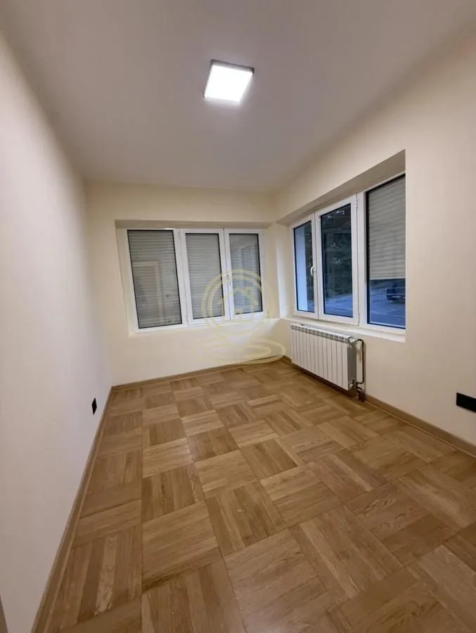 Prazna soba sa parketom i velikim prozorima.