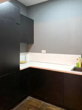 Kuhinja sa crnim elementima i bijelom radnom površinom. - image 4