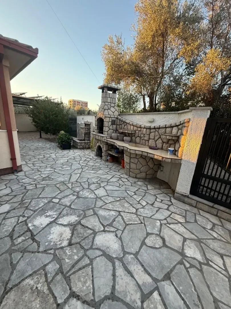 Popločano dvorište sa ugrađenim roštiljem i česmom.