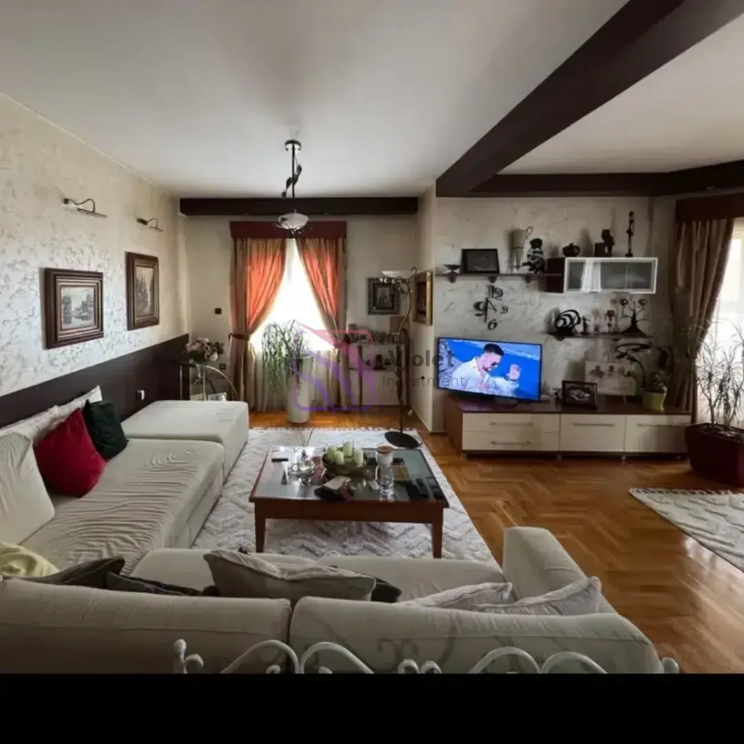 Dnevna soba sa garniturom, stočićem i televizorom.