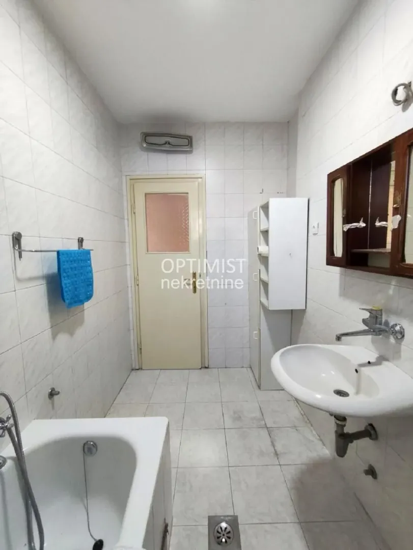 Manje opremljeno kupatilo sa kadom, umivaonikom i pločicama na zidovima.