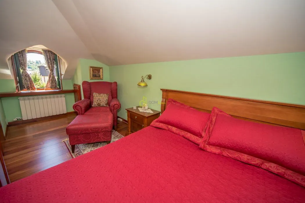 Furnished bedroom with a double bed, an armchair, and an attic window.